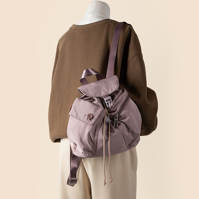 Nylon Drawstring Mini Backpack in lotus pink, worn on one shoulder